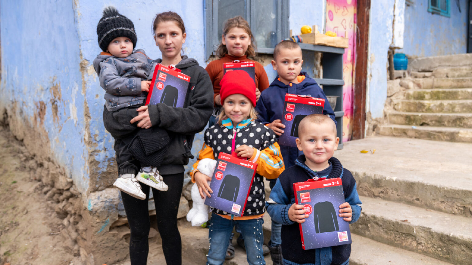 Image of one adult and five children holding HEATTECH items and posing for a photo